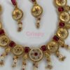 An antique gold-plated necklace and earring set featuring traditional Meena work, likely with red and white stone accents.