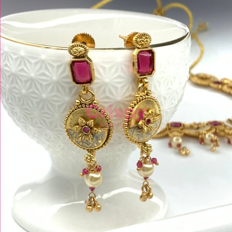 An antique gold-plated necklace and earring set featuring traditional Meena work, likely with red and white stone accents.