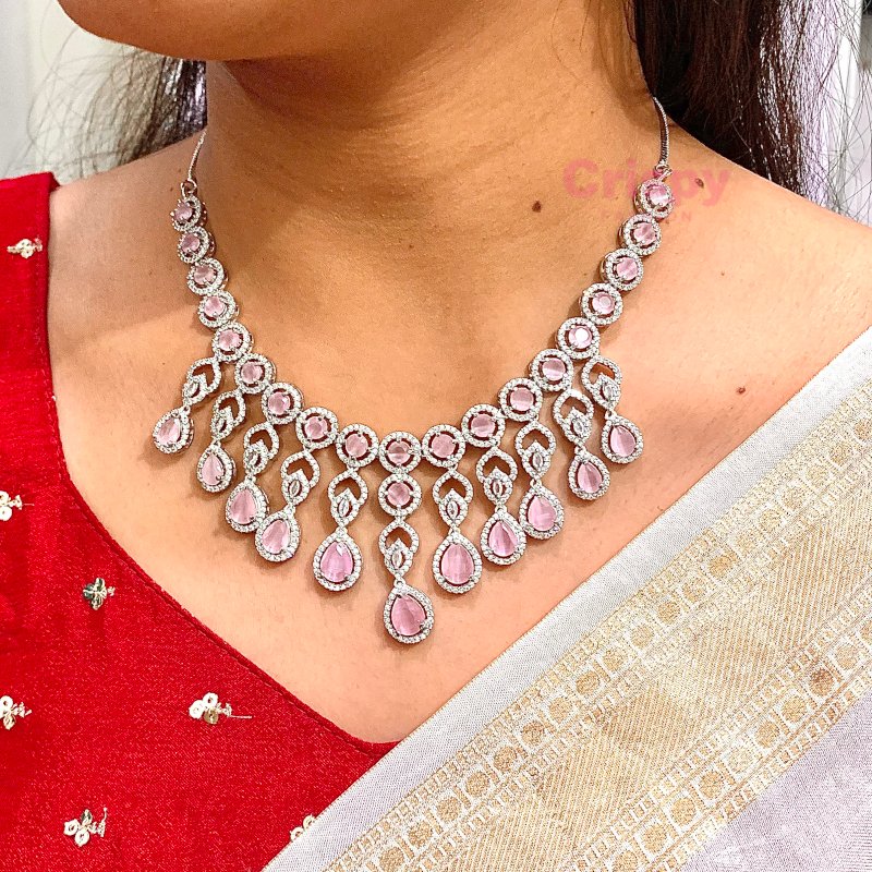 A pink and silver necklace set featuring American diamonds.