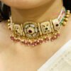 An antique gold-toned choker necklace and earring set featuring intricate designs, pearls, and colorful stones.