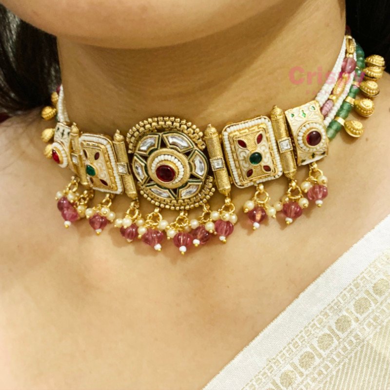An antique gold-toned choker necklace and earring set featuring intricate designs, pearls, and colorful stones.